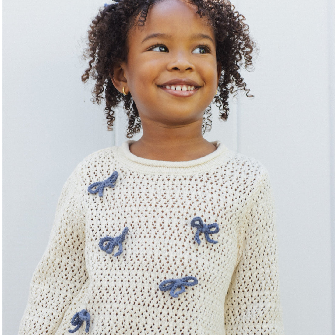 White sweater with blue bow patterns and a blue floral skirt
